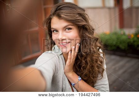 Selfie photo of young woman with flirty look. Travelgirl taking selfie shots in the street, picture made with wide open diaphragm.