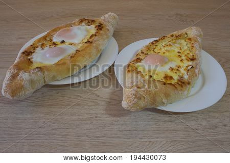 Adjarian Georgian national dish Khachapuri bread with cheese and egg on a plate in a cafe. Khachapuri raditional Georgian cheese-filled bread Ajarian style