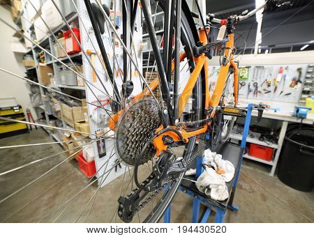 Detail of the transmission of orange broken bike in the mechanical workshop specializing in bicycle repair