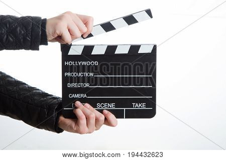 Close-up of hands of girl in black clothes is holding clapperboard on white background