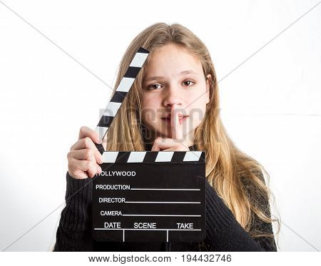 Teenage girl in black clothes, blonde with long hair is holding clapperboard, on white background