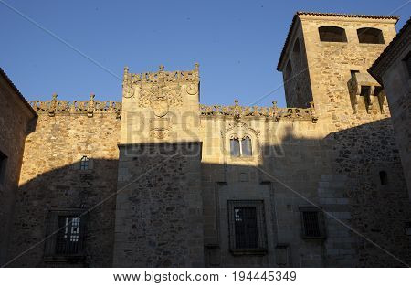 Golfines Palace at sunset. Coat of arms Illuminated by last ray of sun Caceres Spain