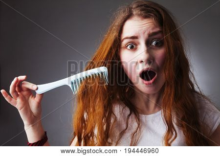 Portrait of a stressed young woman with tousled and disheveled long hair want to comb her hair