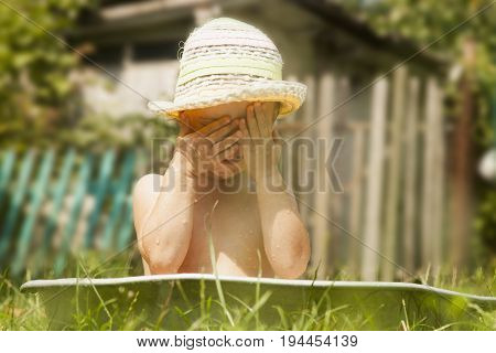 Education of the child in harmony with nature. Little beautiful baby girl taking bath outdoors on the grass in vintage washing-up bowl