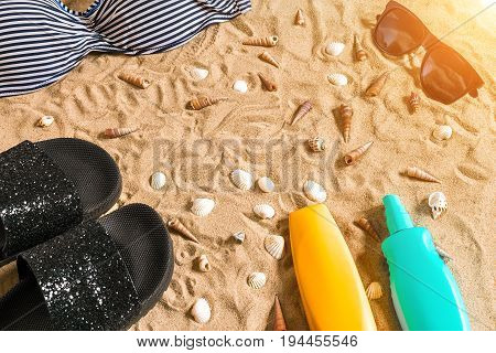 Summer bikini and accessories stylish beach set, Beach bikini summer outfit and sea sand as background, Top View, Concept. Copy space. Sun flare