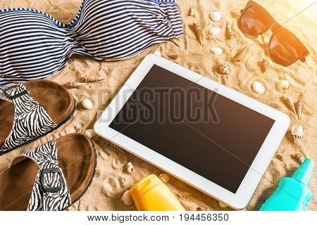 Summer bikini and accessories stylish beach set, Beach bikini summer outfit and sea sand as background, Top View, Concept. Copy space. Sun flare