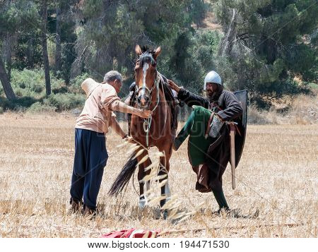 Tiberias Israel July 01 2017 : Participant in the reconstruction of Horns of Hattin battle in 1187 sits on the fighting horse and the second helps him on the way to the battlefield near TIberias Israel