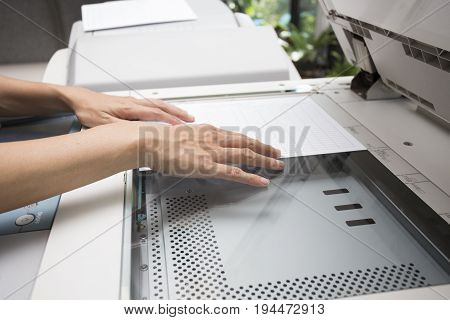 woman hands putting a sheet of paper into a copying device