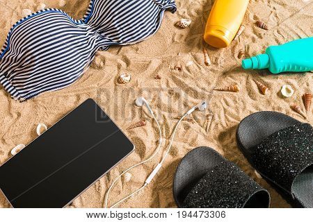 Summer bikini and accessories stylish beach set, Beach bikini summer outfit and sea sand as background, Top View, Concept. Copy space