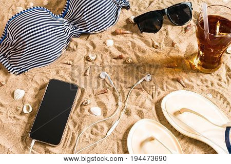 Summer bikini and accessories stylish beach set, Beach bikini summer outfit and sea sand as background, Top View, Concept. Copy space