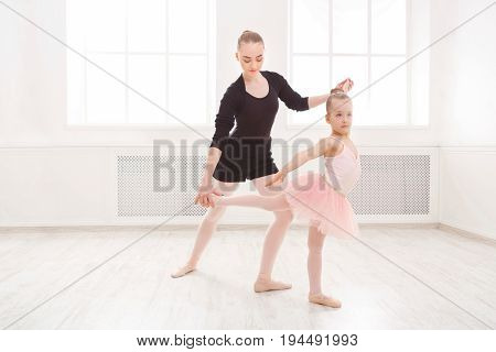 Little girl learning ballet with teacher copy space. Cute small ballerina training classical dance exercises with female coach.