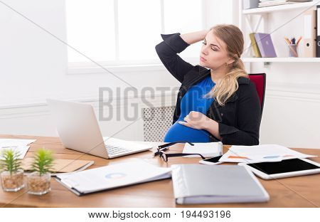 Tired pregnant businesswoman at office copy space. Expectant business lady feeling sick at work, gestosis concept