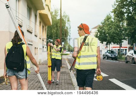 STRASBOURG FRANCE - MAY 30 2017: Students from the Institut National des Sciences Appliquees de Strasbourg performing a survey by theodolite for civil engineer checking surveyor equipment tachometer or theodolite outdoors at construction site in modern Fr