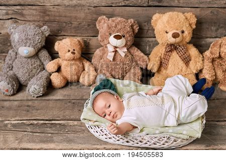 Basket, baby and teddybears. Kid on wooden background.