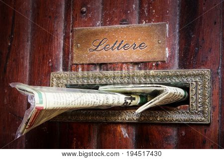 PERUGIA, ITALY. October 26, 2013: Mailbox newspaper inserted into wood doorway, old building house in the city center of Perugia in Italy.