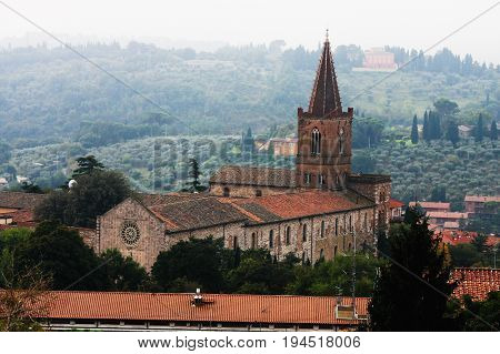 Historic church of Perugia, Umbria region in Italy. View of the roof of an old historic church in Perugia, Italy. Panorama with plants, trees and vegetation. Light early morning mist.