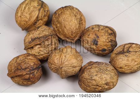 Some whole walnuts on a table painted in grey