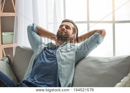 Young male relaxing on sofa indoors carefree sleeping
