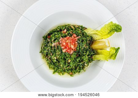 Arabic traditional salad Tabbouleh with Fresh Parsley, Tomatoes, Cracked Wheat, Onions, Freshly Squeezed Lemon Juice Virgin Olive Oil.