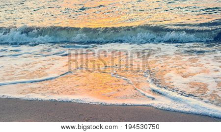abstract background - orange sunrise reflecting off the waves crashing on the shore