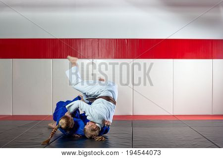 Two young  women fight judo on tatami