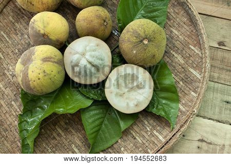 Santol fruit yellow color Middle cut on Santol leaves and wood basket.