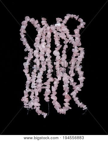 Polished rose quartz strings on black background