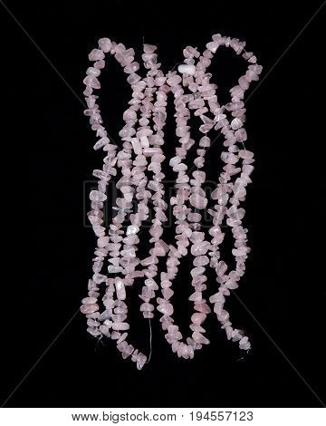 Polished rose quartz strings on black background
