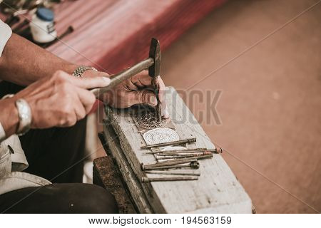 North Thai senior artist handcraft carver silver with hammer and chisel for culture style silver art craft at Chiang Mai Thailand.