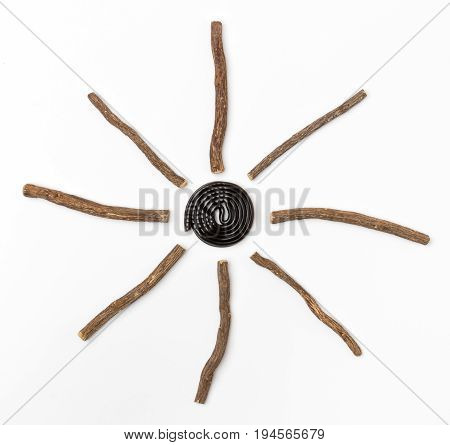 Liqorice roots and black wheel on white background. Top view.
