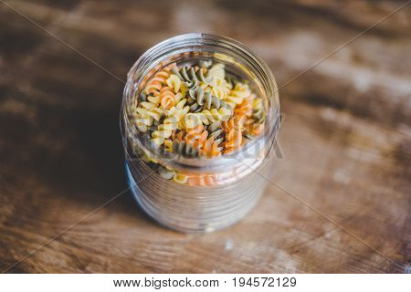 selective focus of italian pasta in glass jar on wooden table