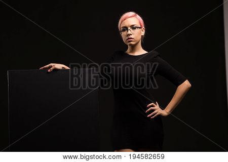 Young sexy woman portrait of a confident businesswoman showing presentation, pointing placard bkack background. Ideal for banners, registration forms, presentation, landings, presenting concept.