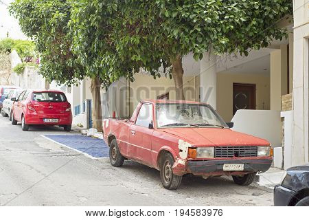 Agis Nikolaos, Crete, Greece - June 13, 2017: Old rusty red car parked in the street