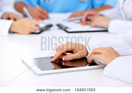 Group of doctors at medical meeting. Close up of physician using tablet computer