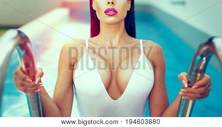 Sexy wet woman with big titis at swimming pool in sunset color graded