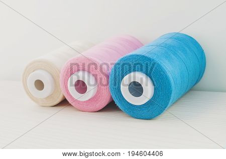 sewing thread blue pink beige are on the table