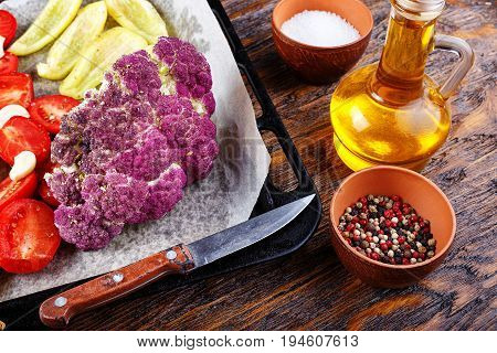 Vegetables on a baking sheet tomatoes cauliflower paprika next to the spices and olive oil