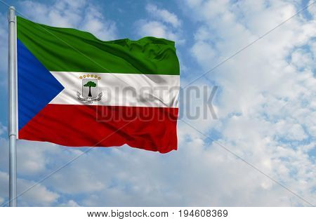 National flag of Equatorial Guinea on a flagpole in front of blue sky.
