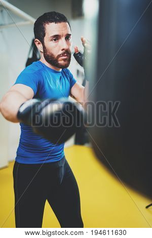 Concept of a healthy lifestyle.Young athlete fighter practicing kicks with punching bag.Kick boxer boxing as exercise for the fight.Boxer man hits punching bag.Vertical