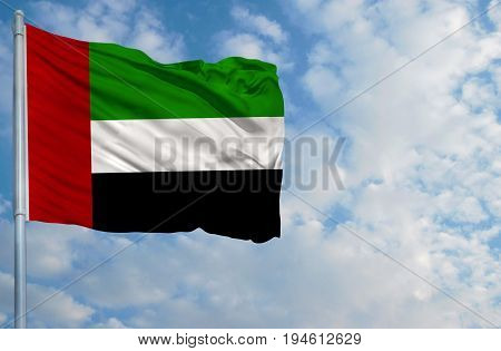 National flag of United Arab Emirates on a flagpole in front of blue sky.