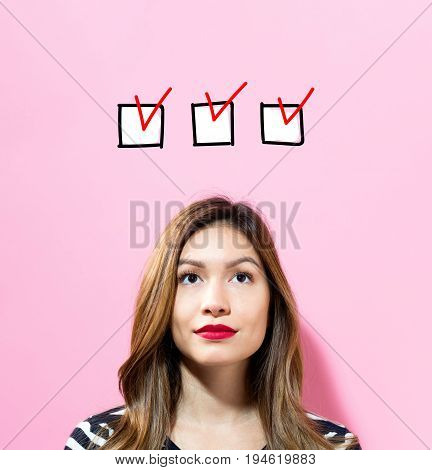 Checklist with young woman on a pink background