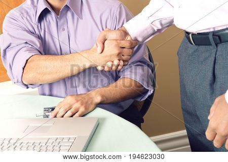 Two business men shaking hands in office, mid section