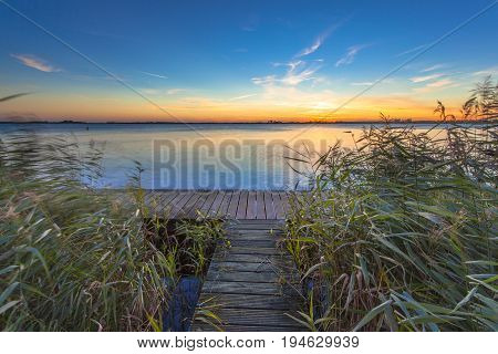 Long Exposure Image Of Sunset Over Boardwalk On The Shore Of A Lake