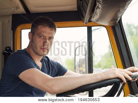 Male trucker in cabin of his yellow truck.