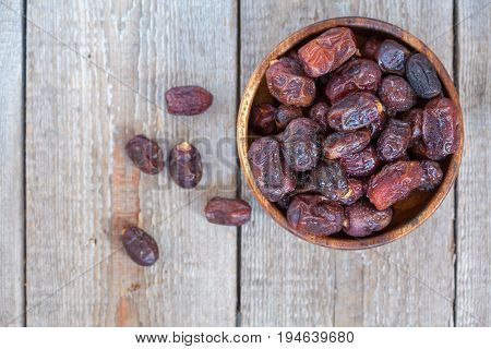 Fresh dates in wooden bowl. Love for a healthy vegan food concept.
