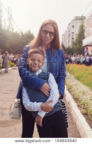 The first time in first class: happy schoolboy with his mother going to the school in first time