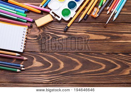 Frame from stationery - pencils pen note erazer paint on wooden background. Back to school. Top view. Place for text.