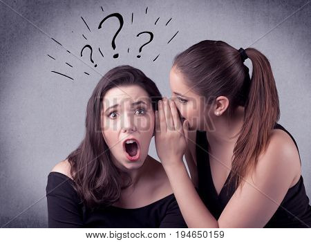 A teenager girl looking confused with drawn question marks above the head, while a girlfriend whispers something in her ear concept.