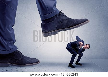 Young handsome businessman getting crushed by a big formal shoe