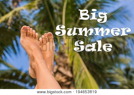 Feet up infront of palm and palm leaves. Words: Big summer sale.